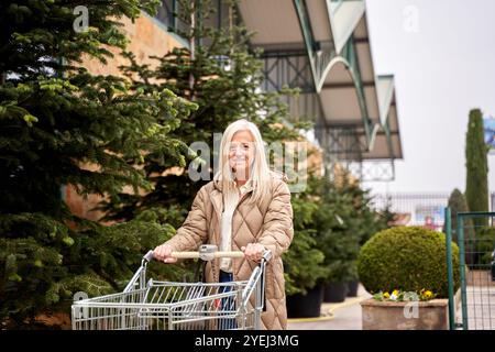 Eine Frau schiebt einen Einkaufswagen in einem Laden. Sie lächelt und genießt ihr Einkaufserlebnis Stockfoto