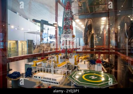 Ein detailliertes Modell einer Offshore-Bohrinsel, das in einer Museumsausstellung ausgestellt ist, umgeben von einem Glaskasten mit lebhaften Farben und komplizierten Strukturen. Stockfoto