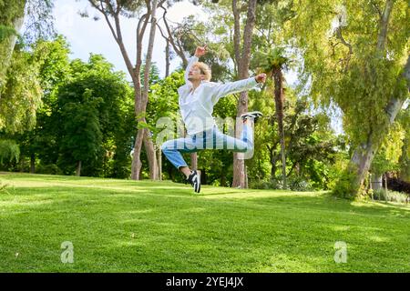 Junger Mann springt und tanzt zeitgenössisches Ballett im Park mit urbaner Tracht. Stockfoto