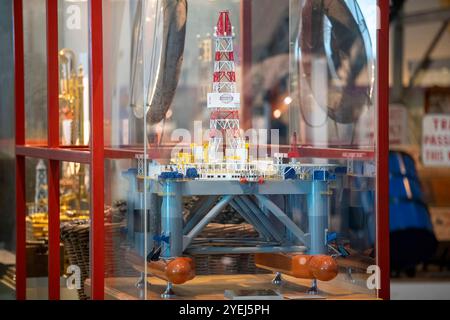 Ein detailliertes Modell einer Offshore-Bohrinsel, das in einer Museumsausstellung ausgestellt ist, umgeben von einem Glaskasten mit lebhaften Farben und komplizierten Strukturen. Stockfoto