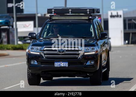 Toyota Land Cruiser mit Dachträger und montierter Dachbox fährt auf einer Vorstadtstraße und präsentiert ein robustes, modernes Fahrzeug mit Geländegängigkeit. Stockfoto