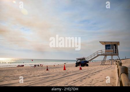 Das Foto zeigt eine Rettungsstation an einem Sandstrand mit einem Rettungswagen, der in der Nähe geparkt ist. Stockfoto