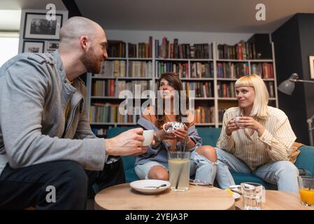 Gruppe kreativer und intelligenter junger Studenten, die über Arbeit diskutieren, Ideen für ein Projekt austauschen und ein Meeting in einer Café-Bibliothek mit Co-Working Space halten. Teamwork Stockfoto