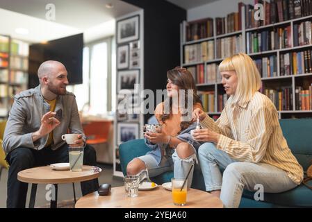 Gruppe kreativer und intelligenter junger Studenten, die über Arbeit diskutieren, Ideen für ein Projekt austauschen und ein Meeting in einer Café-Bibliothek mit Co-Working Space halten. Teamwork Stockfoto