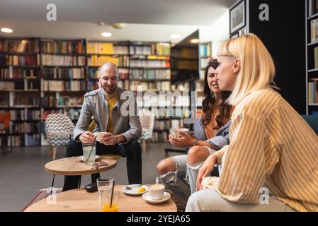 Gruppe kreativer und intelligenter junger Studenten, die über Arbeit diskutieren, Ideen für ein Projekt austauschen und ein Meeting in einer Café-Bibliothek mit Co-Working Space halten. Teamwork Stockfoto