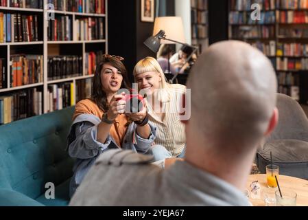 Gruppe kreativer und intelligenter junger Studenten, die über Arbeit diskutieren, Ideen für ein Projekt austauschen und ein Meeting in einer Café-Bibliothek mit Co-Working Space halten. Teamwork Stockfoto