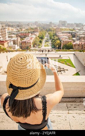 Rückansicht Frau, die Fotos von einer malerischen urbanen Landschaft in Jerewan City macht, mit einem Fernblick auf die berühmten Wolken, die den Mount Ararat und Cascade Comp bedeckten Stockfoto