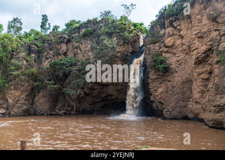 Die Malika Falls im Nakuru National Park, Kenia, sind ein atemberaubender Wasserfall, der sich über felsige Klippen stürzt und von üppigem Grün umgeben ist. Das Wasser fließt in einen kleinen Pool, der Nebel und ein beruhigendes Geräusch erzeugt, während die lebhafte Vegetation um die malerische Schönheit der Szene beiträgt. Stockfoto