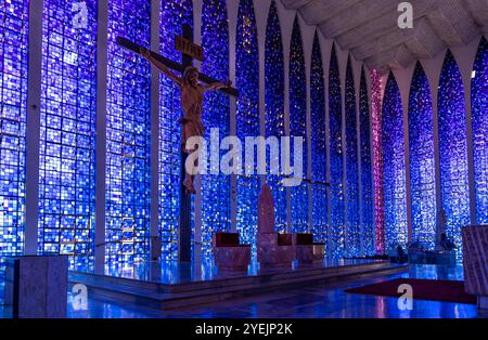 Großes Kruzifix im Altar, das vor einem atemberaubenden blauen Buntglas in der Basilika Dom Bosco in Brasilia steht Stockfoto