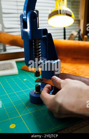 Nahaufnahme der Hände des Meisters, die handgefertigte Lederprodukte nähen. Ein Männerbräuner verbindet die Teile und schafft hochwertige Lederaccessoires. Arbeitsvorgang Stockfoto