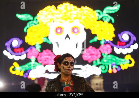 Mexiko-Stadt, Mexiko. 30. Oktober 2024. Eine Frau wird vor dem Hintergrund einer Lichtinstallation für den Tag der Toten auf dem Zocalo Square in Mexico City, Mexiko, 30. Oktober 2024 dargestellt. Quelle: Francisco Canedo/Xinhua/Alamy Live News Stockfoto