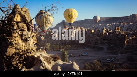 Die atemberaubende Landschaft Kappadokiens wird bei Sonnenaufgang mit farbenfrohen Heißluftballons beleuchtet, die sich über markanten Felsformationen erheben Stockfoto