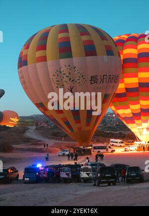 Am frühen Morgen in Kappadokien sehen Sie lebendige Heißluftballons, die bereit sind, die Landschaft zu beleuchten, während Reisende sehnsüchtig auf das Abenteuer aus der Luft warten Stockfoto