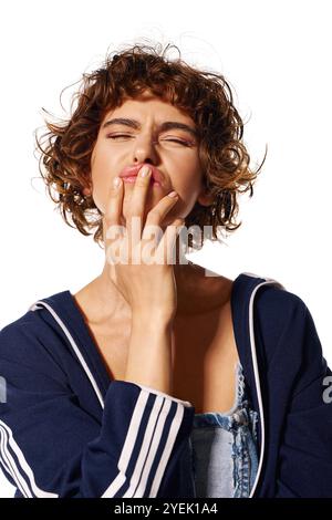 Eine junge Frau scheint besinnlich und berührt ihre Lippen mit einer Furche. Stockfoto