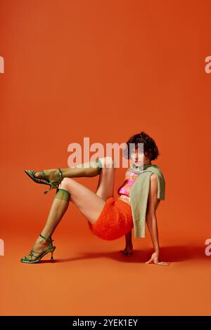 Eine junge Frau drückt innige Emotionen aus und zeigt farbenfrohe Mode in einer auffälligen Pose. Stockfoto