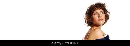 Eine junge Frau mit lockigem Haar spiegelt ihre Emotionen vor einem schlichten Hintergrund wider, elegant gekleidet. Stockfoto