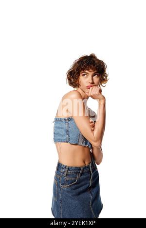 Die junge Frau drückt tiefe Emotionen aus und trägt ein stylisches Denim-Outfit. Stockfoto