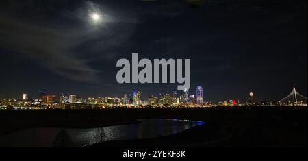 Malerischer Blick auf die Skyline von Downtown Dallas vom Trammell Crow Park mit leuchtendem Mond, das Sill Waters reflektiert Stockfoto