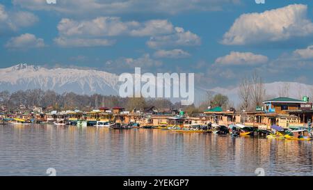 Elegante Hausboote, die im Dal-See Kaschmir ankern, schneebedeckte Himalaja sind im Hintergrund. Stockfoto