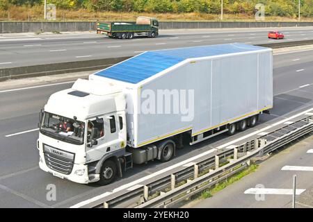 Fahrer und Sicherheitsgurt von DAF-LKW in der Kabine eines sauberen, weißen Lkws, der nicht gekennzeichnete Sattelauflieger mit knickgelenktem, starrem Auflieger zieht, der auf der M25-Autobahn in England in Großbritannien fährt Stockfoto