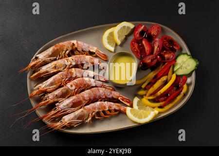 Gebratene Garnelen auf Teller mit frischem Gemüse und Zitronenscheibe. Meeresfrüchte im Hintergrund. Stockfoto