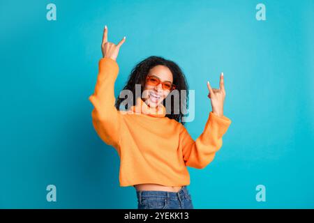 Foto des charmanten positiven Mädchens tragen orange Pullover, der har Rock Schilder zeigt leeren Raum isolierte blaue Farbe Hintergrund Stockfoto