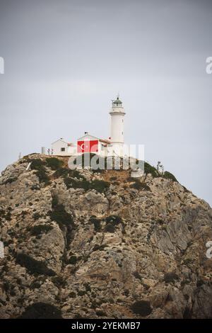 Ein Leuchtturm an einem felsigen Ufer mit Wasser im Hintergrund an einem bewölkten Tag Stockfoto