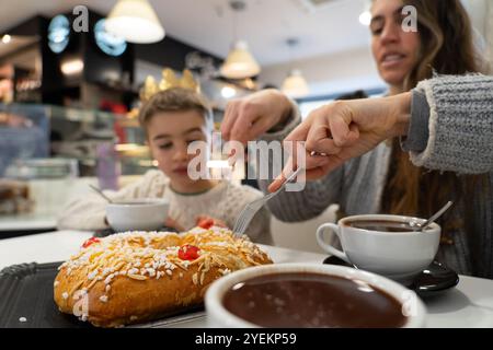 Mutter und Sohn in einer Cafeteria am Tag der drei Könige beim Frühstück von roscón de reyes mit typisch spanischer heißer Schokolade am 6. Januar Stockfoto