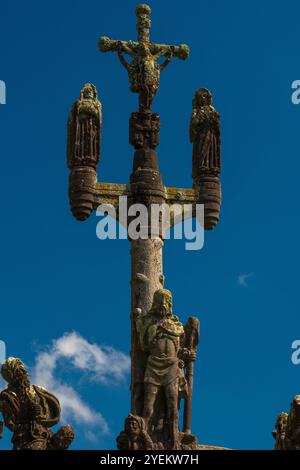 Christus am Kreuz (Vorderansicht) auf dem Gipfel des Kalvariums Ende der 1500er Jahre in der Pfarrei nahe der Eglise Saint-Miliau in Guimiliau, Finistère, Bretagne, Frankreich. Zwei Engel sammeln Blut von Christi Füßen und zwei andere aus seinen Händen. Die Jungfrau Maria befindet sich auf der linken Seite und der Heilige Johannes der Geliebte auf der rechten Seite. Stockfoto