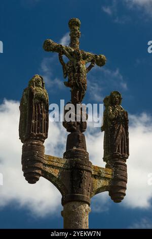 Die Skulptur wurde Ende der 1500er Jahre erbaut, Christus am Kreuz (Vorderansicht) auf dem Gipfel des Kalvariums in der Pfarrei nahe der Eglise Saint-Miliau in Guimiliau, Finistère, Bretagne, Frankreich. Zwei Engel sammeln Blut von Christi Füßen und zwei weitere Engel aus seinen Händen. Die Jungfrau Maria befindet sich links vom Kreuz und der Heilige Johannes der Geliebte rechts. Stockfoto