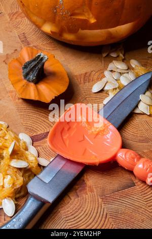 Vorbereitung für Halloween, Kürbisfleisch und Samen mit Schnitzerei auf Holzbrett Stockfoto