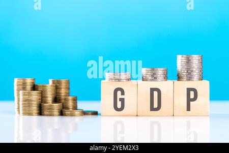 Ein Holzblock mit der Aufschrift "GDP" neben einem Stapel Münzen. Symbolisiert Wirtschaftswachstum und betont die Bedeutung des Bruttoinlandsprodukts in der Bewertung Stockfoto