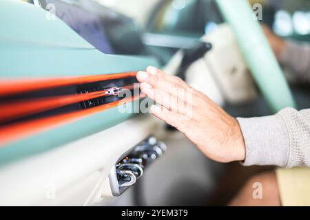 Der Autobesitzer überprüft die Klimaanlage, indem er die kühle Luft aus der Entlüftung spürt, nachdem das Fahrzeug überflutet wurde. Konzept der Fahrzeugwartung, Stockfoto