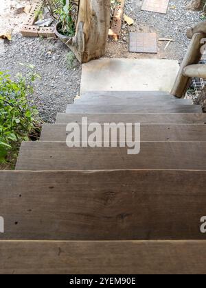 Die Holztreppe aus Teakholz führt hinunter zur Veranda des örtlichen Bauernhauses, Vorderansicht des Kopierraums. Stockfoto