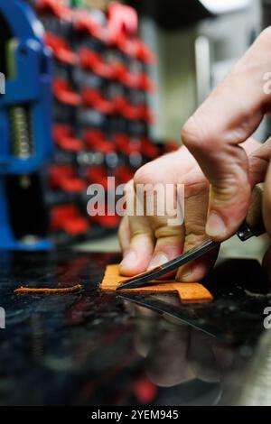 Die Hand eines Mannes hält Lederstücke für eine Ledertasche in seiner Werkstatt. Der Prozess der Arbeit mit naturbraunem Leder. Der Handwerker hält den Stockfoto