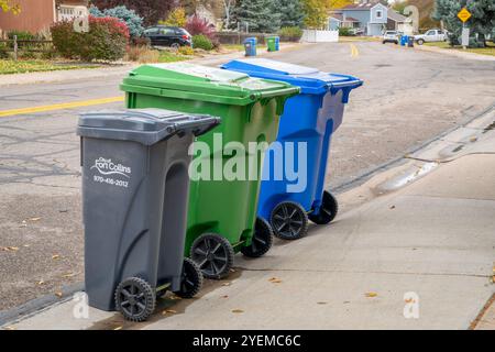 Fort Collins, CO, USA - 30. Oktober 2024: Müllabfuhr - drei Container auf einer Straße für Hausmüll, Gartenabbau und recycelbare Matte Stockfoto