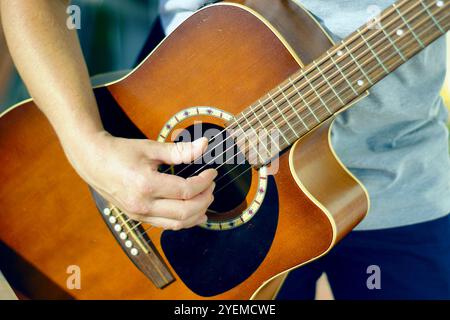 Musikunterricht: Person spielt Akustikgitarre. Kreativität in der Freizeit: сlose-up einer Männerhand, die die Saiten einer klassischen Gitarre zupft. Stockfoto