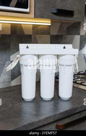 Wasserfiltersystem mit austauschbaren Kartuschen. Ein System in einer Wohnung mit drei Tanks zur Reinigung von Wasser unter dem Wasserhahn. Stockfoto