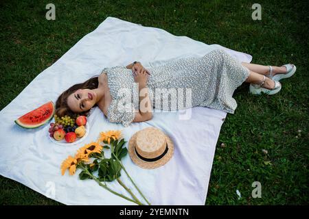 Sommer-Picknick: Ein entspannender Nachmittag auf einer Decke umgeben von frischem Obst und Blumen. Stockfoto