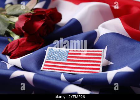 Veteranentag. Amerikanische Armee Patch und Rosenblumen auf der US-Flagge, Nahaufnahme Stockfoto