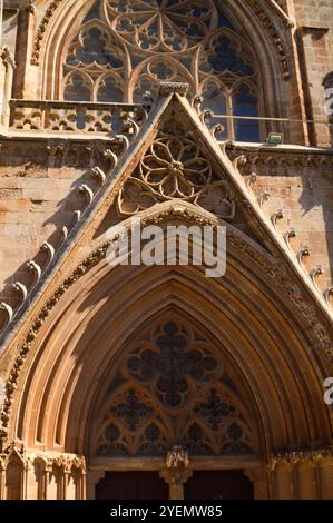Ein atemberaubender gotischer Eingang zeigt kunstvolle Steinschnitzereien und komplizierte Details, die von Sonnenlicht warm beleuchtet werden. Stockfoto
