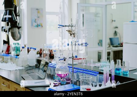 Labor mit modernen Chemiegeräten und verschiedenen Glasapparaten für Experimente mit farbigen Flüssigkeiten, die dem Arbeitsbereich mehr Lebendigkeit verleihen Stockfoto