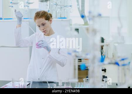 Wissenschaftler, die mit wissenschaftlichen Geräten im Labor arbeiten, chemische Experimente mit Präzision in kontrollierter Umgebung durchführen und Schutzausrüstung tragen Stockfoto