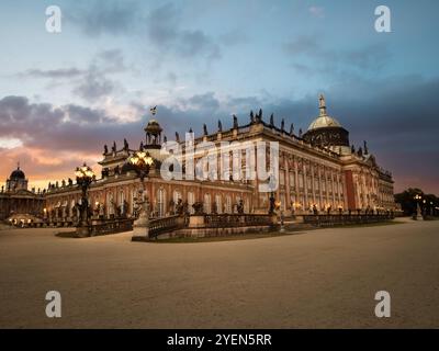 Abendblick auf Schloss Sanssouci und Neuen Palast in Potsdam, Deutschland, mit barocker Architektur, beleuchtet durch sanfte Beleuchtung und einem ruhigen Abendhimmel Stockfoto