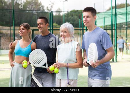 Porträt von vier glücklichen Padel-Spielern auf dem Tennisplatz im Freien Stockfoto