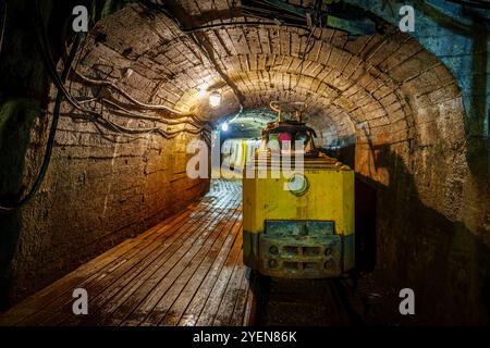 Rusty Yellow Mining Train transportiert Erz in dunklem Tunnel mit Holzboden und dunkler Beleuchtung, cooper Mine Stockfoto