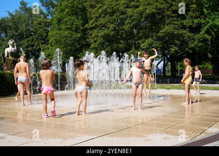 Juli 2023. Warschau, Polen. Glückliche Kinder spielen am heißen Sommertag im Brunnen der Stadt. Kühlung in den Wasserstrahlen. Stockfoto