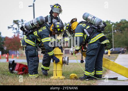 Von links, Mr. Robert Bowen, U.S. Air Force Tech. Sgt. Jaime Torres-Rivera und Albert Siu, 177th Civil Engineer Squadron Fire and Emergency Services Firefighters, errichten eine Versorgungsleitung, um Wasser aus einem Hydranten zu holen, um einen kontinuierlichen Fluss zu den Angriffslinien zu gewährleisten, die in ein Gebäude gestreckt wurden, während eines strukturellen Live-Fire-Trainings an der Atlantic County Fire Academy, das sich im Anthony 'Tony' Canale Fire Training Center in Egg Harbor Township, New Jersey, 24. September 2024 befindet. Das Training bestand darin, die Struktur von Rauch, Hitze und giftigen Gasen zu belüften und durch die Struktur zu gelangen Stockfoto