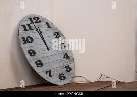 Rustikale Vintage-Wanduhr, die sich an eine Wand lehnt. Stockfoto