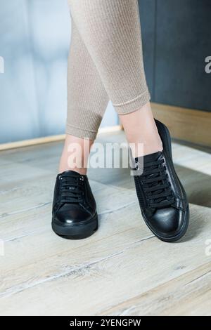 Kollektion von Damenschuhen. Schwarze Lederschuhe an den Füßen von Frauen. Weibliche Füße in bequemen, legeren Sandalen Stockfoto